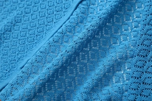 Detail of blue knit dress featuring intricate diamond hollow crochet texture and patterns