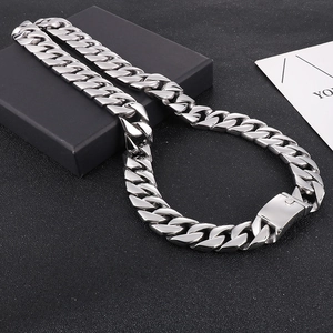 Détail macro d'un collier chaîne cubaine de 20 mm en acier poli sur socle noir