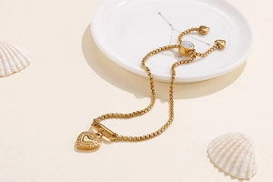 Detailed shot of adjustable gold heart chain bracelet on a ceramic zodiac plate