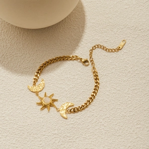Macro detail of sun and moon charms on 18K gold plated stainless steel Cuban bracelet