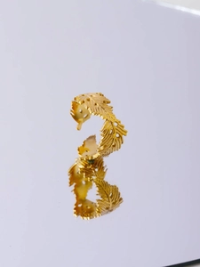 Detailed view of adjustable golden feather ring with intricate engraved textures