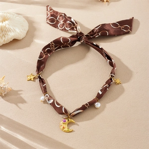 Collier ruban en soie marron avec étoiles, lunes dorées et perles sur fond de plage