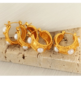 Detail of vintage French 18k gold C-shaped earrings with white pearls on a stone base