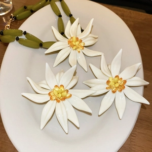 Detail of floral jewelry set with green oval beads and large white resin flowers