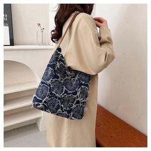 Detail of blue washed denim tote bag with white distressed floral lace texture and leather strap