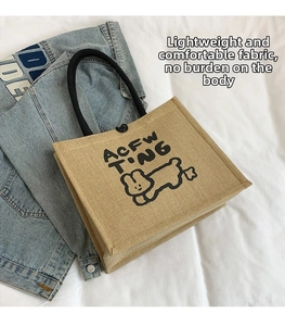 Close-up of linen tote bag with black rope handles and a cute cartoon animal print