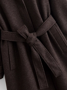 Close-up of a dark coffee wool coat featuring a textured waist belt and tied knot detail