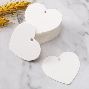 Detailed view of blank white heart-shaped paper gift tags on marble surface background