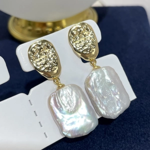 Macro detail of baroque freshwater pearls with textured golden studs on jewelry card