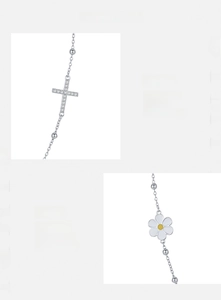 Detail of s925 silver necklace with sparkling cubic zirconia cross and white daisy charm