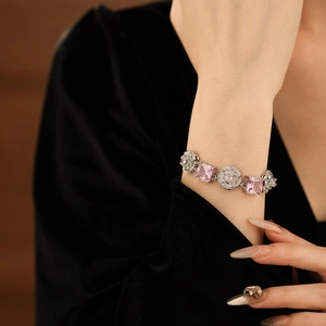 Detailed view of silver flower bracelet with pink square gemstones on model wrist