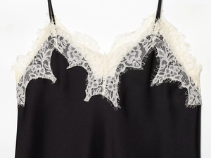 Detailed view of black satin fabric with intricate white eyelash lace trim edges