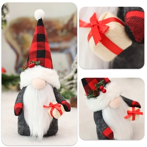 Detail of a Christmas gnome plush with red plaid hat holding a beige gift box ornament