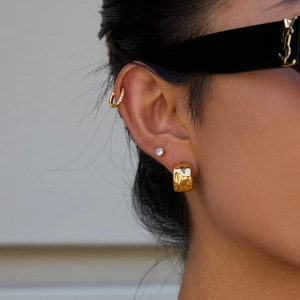Detail of model wearing textured gold geometric hoop earrings and stud jewelry set