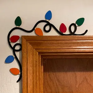 Close-up of colorful wooden Christmas light string decor on a white door frame corner