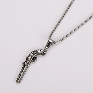 Detailed macro view of vintage stainless steel pistol pendant with ornate black engravings