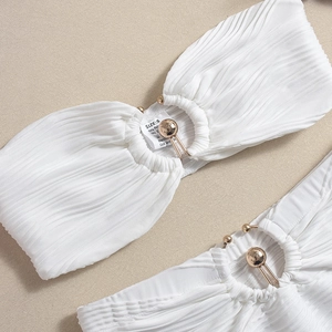 Detail of white pleated fabric two-piece set featuring gold ball metal buckle ornaments