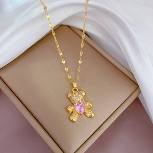 Macro shot of bear pendant with pink heart zircon on golden titanium steel necklace