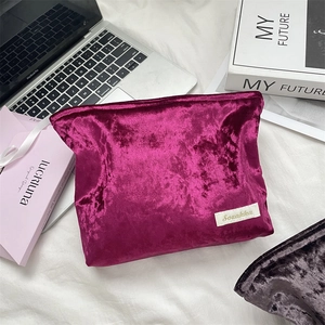 Detail of fuchsia velvet makeup bag showing smooth texture and Sozakka brand woven label