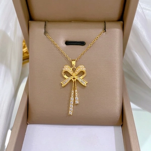 Gold titanium steel necklace set featuring a bow pendant with pearls and crystal tassels