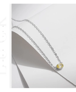Detail of s925 silver necklace with oval yellow gemstone pendant on elegant white curves