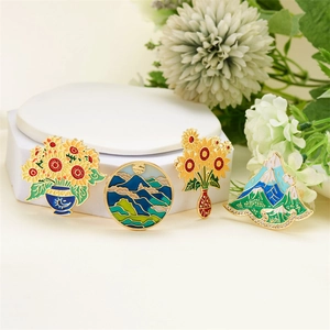 Set of four vintage enamel pins featuring sunflower and landscape designs on gold metal