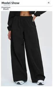 Detail of high-waisted black wide-leg sports trousers with elastic waist on model
