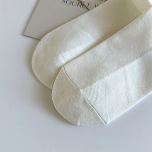 Detail shot of white knitted cotton socks showing fine texture and premium toe stitching