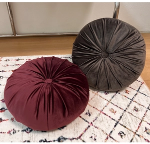 Detailed texture of round velvet pumpkin pillows with pleated fabric and center buttons