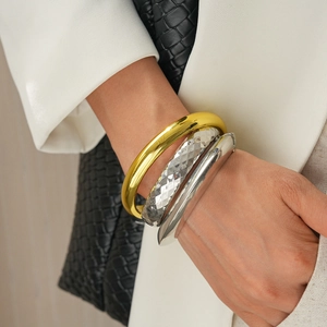Close-up of stacked gold and silver geometric metal bangles on a model's wrist