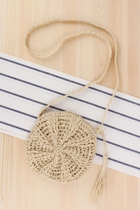 Detailed view of handmade circular straw bag with woven paper rope and decorative tassel