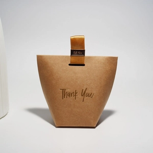 Detail of brown kraft gift bag with gold ribbon handle and Thank You gold foil text