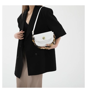 White leather saddle bag with golden lock and tortoiseshell chain detail on a model