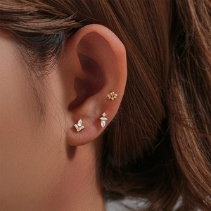 Detailed view of 925 sterling silver gold stud earrings with clear zircon on a model ear