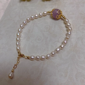 Detailed macro view of baroque pearl bracelet with purple bead in gold filigree setting