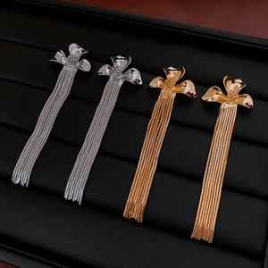 Detail shot of gold and silver flower tassel earrings on a black leather jewelry tray