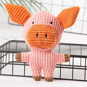 Detailed texture of pink corduroy pig squeaky toy on black metal grid with green plant