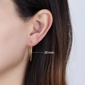 Detail shot of 28mm golden hoop earring worn on ear showing polished sterling silver finish