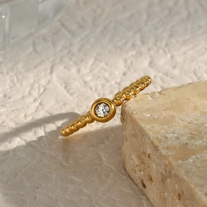 Macro shot of 18K gold plated beaded ring with a sparkling round zircon on stone