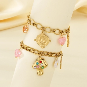 Detail of gold Cuban chain bracelet featuring colorful mushroom, heart, and coin charms