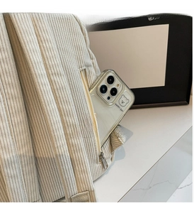 Detail of off-white corduroy backpack side zipper pocket showing storage for smartphone
