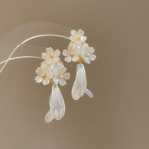 Vue détaillée des boucles d'oreilles fleurs en perles avec pétales blancs et accents dorés