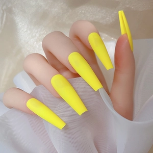 Gros plan d'ongles longs cercueil jaune citron mat portés sur main avec fond en tulle