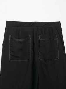 Detail of black straight pants with elastic waist and contrast brown stitching
