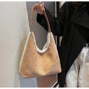 Detail of plush trim and suede texture on khaki underarm tote bag held by model