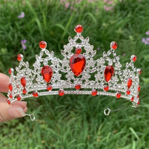 Close-up of hand holding a silver bridal crown with red and clear rhinestones
