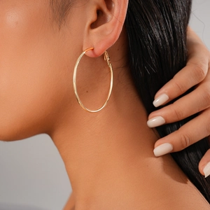 Polished gold large hoop earrings shown on a model with minimalist geometric design