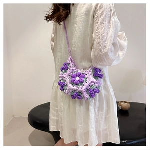 Detail shot of a handmade crochet crossbody bag with purple 3D flowers and pearl accents