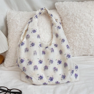 Detail of embroidered purple floral pattern on beige canvas shoulder bag for women