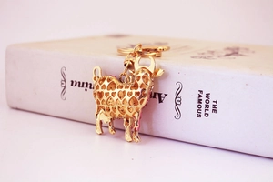 Detailed close-up of golden cow keychain with hollow heart pattern on white book